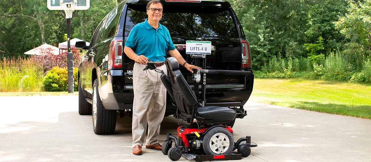 a man standing next to a scooter lift behind a suv