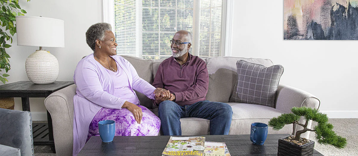 happy couple holding hands while sitting on a couch