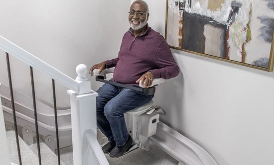 a man riding an elite curved indoor stair lift