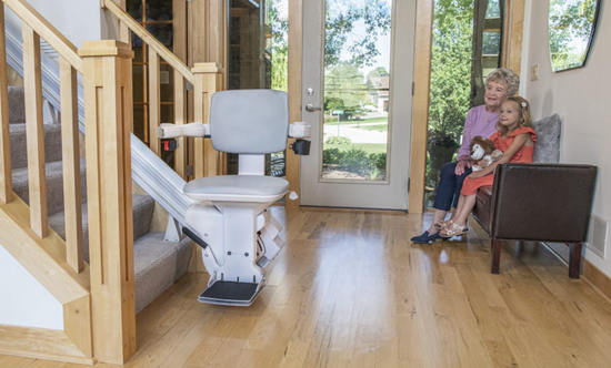 stair lift with an elderly woman and young child sitting on an entryway bench looking at it