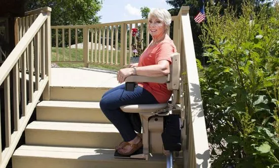 an elderly woman riding an outdoor stair lift
