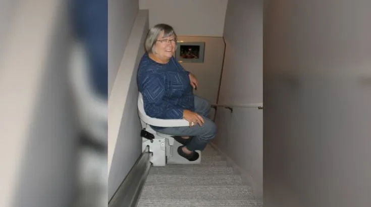 a woman riding an indoor stair lift