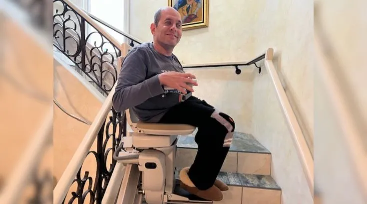 a man riding a curved indoor stair lift