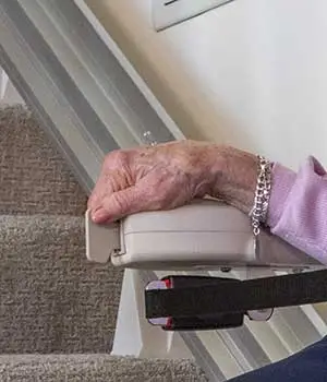 woman pushing the move lever on an elite straight indoor stair lift